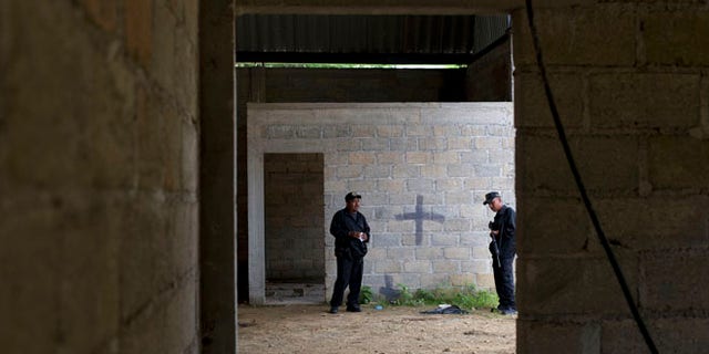 FILE - In this July 3, 2014 file photo, state police stand inside a warehouse where a black cross marks a wall near blood stains on the ground, after a shootout between Mexican soldiers and alleged criminals in Tlatlaya, Mexico. A Mexican civilian court has freed the final three soldiers accused of homicide in the 2014 incident in which suspects were allegedly executed after they surrendered. The federal Attorney Generalâs Office said late Friday, May 13, 2014, the three were absolved of charges of homicide, cover-up and alteration of evidence. (AP Photo/Rebecca Blackwell, File)