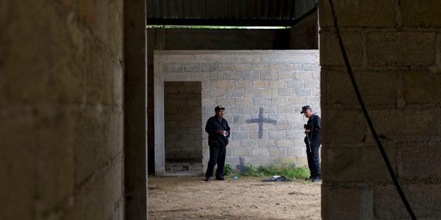 FILE - In this July 3, 2014 file photo, state police stand inside a warehouse where a black cross marks a wall near blood stains on the ground, after a shootout between Mexican soldiers and alleged criminals in Tlatlaya, Mexico. A Mexican civilian court has freed the final three soldiers accused of homicide in the 2014 incident in which suspects were allegedly executed after they surrendered. The federal Attorney Generalâs Office said late Friday, May 13, 2014, the three were absolved of charges of homicide, cover-up and alteration of evidence. (AP Photo/Rebecca Blackwell, File)
