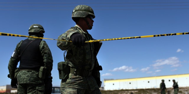 JUAREZ, MEXICO - MARCH 24: A member of the Mexican military police keeps guard over a car with Texas license plates bearing a bullet-ridden body on March 24, 2010 in Juarez, Mexico. Secretary of State Hillary Rodham Clinton, Defense Secretary Robert Gates, and Homeland Security Secretary Janet Napolitano all visited Mexico yesterday for discussions centered on Mexico's endemic drug-related violence. The border city of Juarez, Mexico has been racked by violent drug-related crime recently and has quickly become one of the most dangerous cities in the world in which to live. As drug cartels have been fighting over ever-lucrative drug corridors along the United States border, the murder rate in Juarez has risen to 173 slayings for every 100,000 residents. President Felipe Calderon's strategy of sending 7000 troops to Juarez has not mitigated the situation. With a population of 1.3 million, 2,600 people died in drug-related violence last year and 500 so far this year, including two Americans recently who worked for the U.S. Consulate and were killed as they returned from a child's party. (Photo by Spencer Platt/Getty Images)