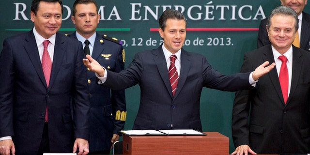 FILE - In this Aug. 12, 2013 file photo, Mexico's President Enrique Pena Nieto, center, greets the audience flanked by the Interior Secretary Miguel Angel Osorio Chong, left, and Energy Secretary Pedro Joaquin Coldwell during the ceremony to announce his proposal that would allow private firms to participate in the oil industry in Mexico City. Legislators from Mexicoâs two pro-energy reform political parties say they support constitutional changes to allow the government to grant licenses and share oil and profits with giants such as Exxon or Chevron. (AP Photo/Eduardo Verdugo, File)