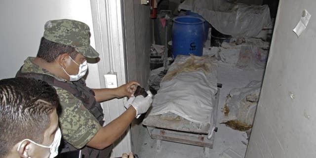 Feb. 6, 2015 - A Mexican army soldier takes photos of a room full of bodies covered with sheets at the crematorium of an abandoned funeral home near Acapulco, Mexico. 61 rotting bodies were discovered Thursday evening at the facility, which had been shuttered for about a year, according to a government official.