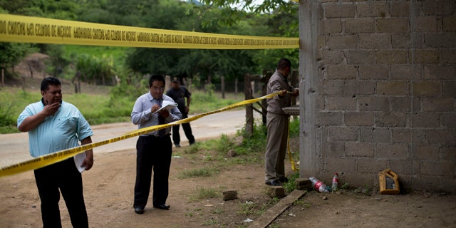 FILE - In this July 3, 2014 file photo, state authorities use crime scene tape to seal off an unfinished warehouse that was the site of a shootout between Mexican soldiers and alleged criminals on the outskirts of the village of San Pedro Limon in Mexico state, Mexico. (AP Photo/Rebecca Blackwell, File)