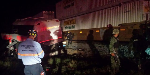 Army soldiers and civil protection workers on the scene of an accident where a passenger bus and a freight train collided at a grade crossing, in Anahuac, Mexico, Friday, Feb. 13, 2015. According to Mexican sources at least 16 people are dead and dozens injured. (AP Photo/El Mañana de Nuevo Laredo)