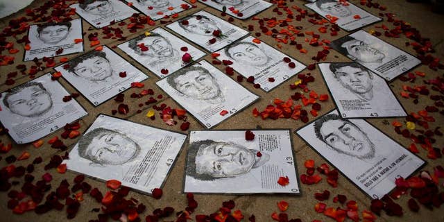 FILE - In this March 26, 2015 file photo, drawings of some of 43 missing rural college students are surrounded by flower petals, forming the shape of a heart, during a protest marking the six-month anniversary of their disappearance, in Mexico City. As millions of Mexicans set up altars to the dead and buy orange flowers to adorn the offerings of food and drink, the parents of 43 students missing since September 2014 are marching, protesting, and seeking other ways to remember their sons, fiercely refusing to accept the government’s explanation that they are dead. (AP Photo/Rebecca Blackwell, File)