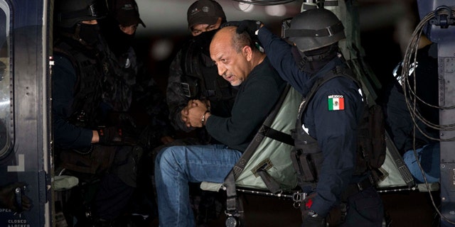 ADDS PHOTOGRAPHER'S BYLINE - Federal police escort who they identify as Servando "La Tuta" Gomez," leader of the Knights Templar cartel, as he sits inside helicopter at the Attorney General's Office hangar in Mexico City, Friday, Feb. 27, 2015. Gomez, a former school teacher who became one of Mexico's most-wanted drug lords as head of the Knights Templar cartel, was captured early Friday by federal police, according to Mexican officials. (AP Photo/Eduardo Verdugo)