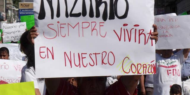 FILE - In this Dec. 12, 2010 file photo, a man holds a sign that reads in Spanish "Nazario will always live in our hearts," referring to La Familia drug cartel leader Nazario Moreno Gonzalez during a demonstration after the government announced he was killed in Apatzingan, Mexico. Years later on Sunday, March 9, 2014, officials say they are trying to determine if a man killed in an early morning shootout is Moreno. Some residents of Michoacan have reported seeing Moreno as his former cartel, La Familia Michoacana, was morphing into the more vicious and powerful Knights Templar. (AP Photo/Primera Plana, File)