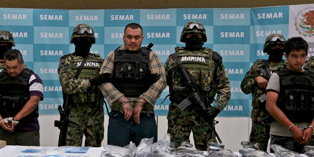 FILE: Navy members escort Martin Omar Estrada Luna, center, alias "El Kilo," and alleged members of his gang in front of seized weapons and packages containing narcotics during a presentation to the press in Mexico City.
