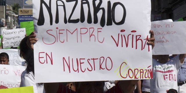 FILE - In this Dec. 12, 2010 file photo, a man holds a sign that reads in Spanish "Nazario will always live in our hearts," referring to La Familia drug cartel leader Nazario Moreno Gonzalez during a demonstration after the government announced he was killed in Apatzingan, Mexico. Years later on Sunday, March 9, 2014, officials say Moreno was killed in an early morning shootout. (AP Photo/Primera Plana, File)