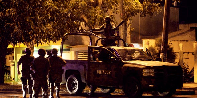 Mexican army soldiers walk towards their vehicle after seven bodies were found inside a vehicle in the Gulf port city of Veracruz, Mexico, late Friday Oct. 7, 2011.