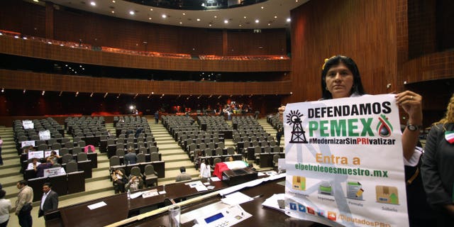 An opposition lawmaker holds a sign in protest against the newly approved energy reform bill in Mexico City, Wednesday, Dec. 11, 2013.