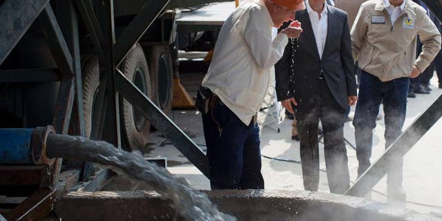 FILE - In this Jan. 23, 2013 file photo, National Water Commission David Korenfeld, center right, watches geologist Federico Mooser take a drink of water from an exploratory well where an aquifer was discovered, in Mexico City. Korenfeld announced his resignation Thursday, April 9, 2015, a week after social media filled with photographs, apparently taken by a neighbor on March 29, showing people walking with suitcases to a helicopter marked with the agency’s name. (AP Photo/Dario Lopez-Mills, File)