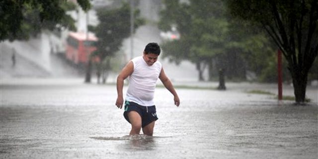 A man walks through a flooded street during heavy rains caused by Tropical Storm Ingrid in the Gulf port city of Veracruz, Mexico, Friday Sept. 13., 2013. (AP Photo/Felix Marquez)