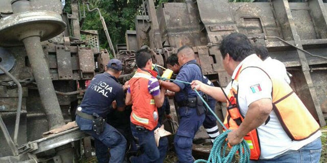 August 25, 2013: In this photo release by the Civil Protection of the State of Tabasco, police agents and rescue workers work at a site where a train derailed in Tabasco, Mexico. (AP Photo)