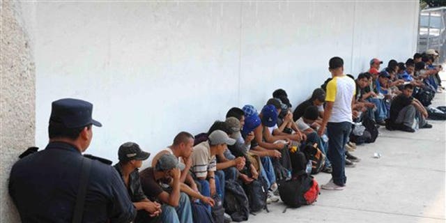 Migrants who were found in two trailer trucks bound for the United States, sit under the guard of a policeman in Tuxtla Gutierrez, Mexico, Tuesday May 17, 2011.  Chiapas authorities say they rescued 513 migrants: 410 of the migrants were from Guatemala, 47 from El Salvador, 32 from Ecuador, 12 from India, six from Nepal, three from China and one each from Japan, the Dominican Republic and Honduras. (AP Photo/Alejandro Estrada)