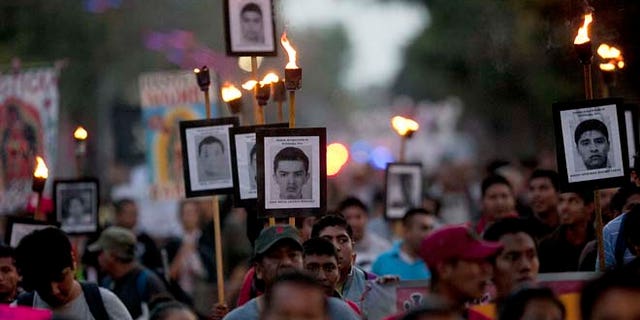 FILE - In this Dec. 26, 2015, file photo, relatives of the 43 missing students from the Isidro Burgos rural teachers college march holding pictures of their missing loved ones during a protest in Mexico City. An appeals court ruling is threatening to derail Mexicoâs effort to prosecute suspects in one of its most notorious crimes of recent years: the disappearance and presumed murder of the 43 students in Guerrero state. (AP Photo/Marco Ugarte, File)