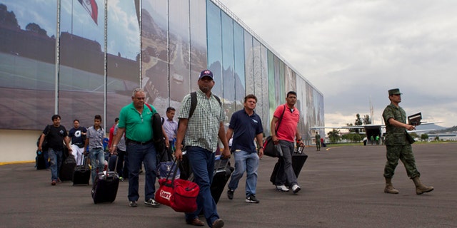 Mexican and foreign tourists arrive at an Air Force hangar in Mexico City after being airlifted out of the hurricane-ravaged resort area of Los Cabos by the Mexican armed forces, in Mexico City, Tuesday, Sept. 16, 2014. Travelers are being flown free of charge to airports in Tijuana, Mazatlan, Guadalajara and Mexico City to catch connecting flights and, in the case of foreigners, receive consular assistance. (AP Photo/Christian Palma)