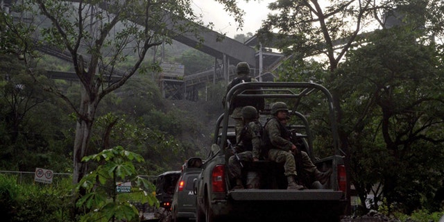In this Aug. 14, 2013 photo, Mexican army soldiers enter the iron ore mine in the town of Aquila, Mexico. A resident of Aquila, said that since 2012, the Knights Templar cartel demanded residents hand over part of the royalty payments from the local iron ore mine operated by Ternium, a Luxembourg-based consortium. Mexican drug cartels long ago moved into oil theft, pirated goods, extortion and kidnapping, but it still came as a shock this month when federal officials revealed the gangs have broadened the scope and sophistication of their economic empires by entering the countryâs lucrative mining industry, exporting iron ore to Chinese and other foreign mills. (AP Photo/Agencia Esquema)