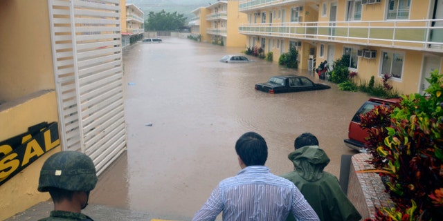 Army soldiers and a civilian look out into a flooded street caused by Tropical Storm Manuel in the city of Chilpancingo, Mexico, Sunday Sept. 15, 2013. (AP Photo/Alejandrino Gonzalez)