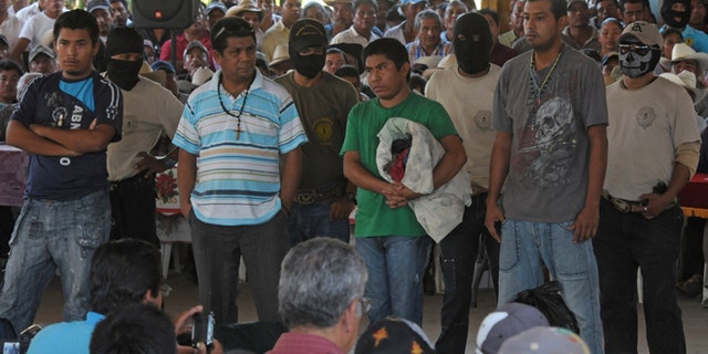 Detained people stand before a community assembly in the town of El Meson, Mexico, Thursday Jan. 31, 2013. Vigilantes who have taken up arms against drug cartel violence and common crime in southern Mexico brought charges ranging from organized crime to kidnapping and extortion against 50 men and three women who they have been holding prisoner at improvised jails, in some cases for weeks. (AP Photo/Bernandino Hernandez)