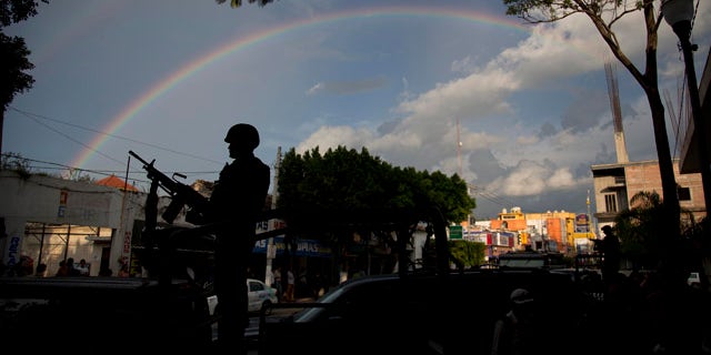October 6, 2014: A soldier stands under a rainbow outside the municipality in Iguala, Mexico. Federal officials on Monday disarmed local police and took over security after an attack on students that left at least six dead and 43 missing. (AP Photo/Eduardo Verdugo)