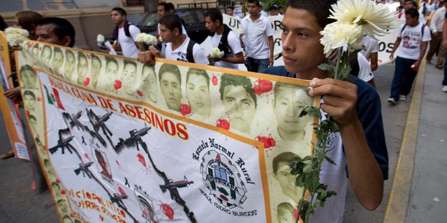 October 14, 2014: Students hold a banner with the faces of the missing that reads in Spanish 'cradle of murders' during a march with flowers and candles to protest the disappearance of 43 students from the Isidro Burgos rural teachers college in Chilpancingo, Mexico. (AP Photo/Eduardo Verdugo)