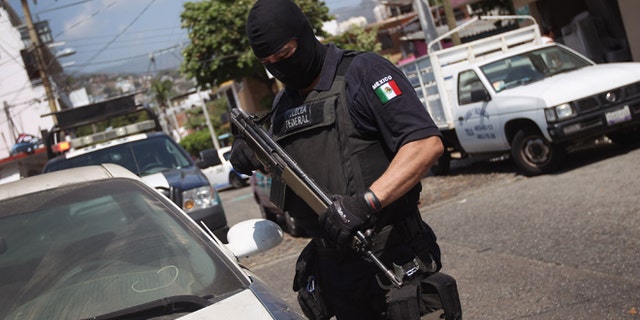 ACAPULCO, MEXICO - MARCH 01: A Mexican federal policeman inspects an abandoned car on March 1, 2012 in Acapulco, Mexico. Stolen vehicles used by drug gangs are often found abandoned throughout the city. Drug violence surged in the coastal resort last year, making Acapulco the second most deadly city in Mexico after Juarez. One of Mexico's top tourist destinations, Acapulco has suffered a drop in business, especially from foreign tourists, due to reports of the violence. Toursim accounts for some 9 percent of Mexico's economy and about 70 percent of the output of Acapulco's state of Guerrero. (Photo by John Moore/Getty Images)