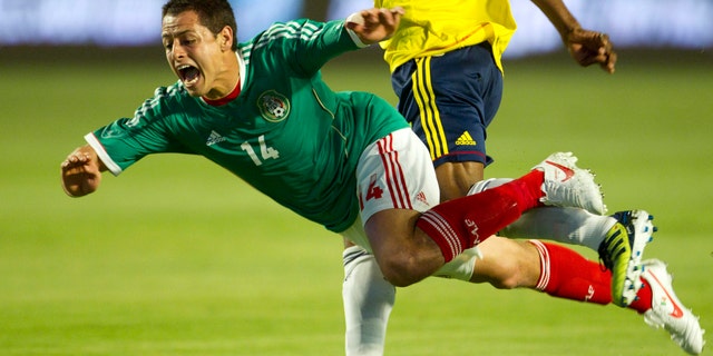 Mexico's Javier Hernandez (14) is knocked to the ground by Colombia's Luis Amaranto Perea (14) during the first period of an international soccer match in Miami, Wednesday, Feb. 29, 2012. (AP Photo/J Pat Carter)