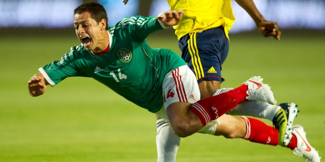 Mexico's Javier Hernandez (14) is knocked to the ground by Colombia's Luis Amaranto Perea (14) during the first period of an international soccer match in Miami, Wednesday, Feb. 29, 2012. (AP Photo/J Pat Carter)