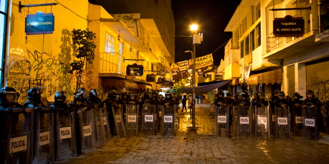 Police stand guard in the pedestrian street where a small explosive was tossed at National Action Party headquarters, in Chilpancingo, Mexico, in the early morning hours of Friday, June 5, 2015. Radical groups and unionized teachers have vowed to block Sunday's voting for the lower house of congress, nine governorships and hundreds of mayorships. (AP Photo/Rebecca Blackwell)