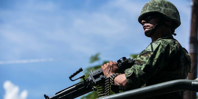 A soldier rides atop a military vehicle in a convoy carrying the bodies of soldiers killed one day earlier in an ambush, inside the Novena Military Zone in Culiacan, Sinaloa State, Mexico, Saturday, Oct. 1, 2016. A brazen ambush on a military convoy Friday left five soldiers dead and 10 wounded in what was the worst attack on military personnel since 2015, when drug cartel gunmen in the state of Jalisco shot down an army helicopter with a rocket launcher, killing 10 people.(AP Photo/Rashide Frias)