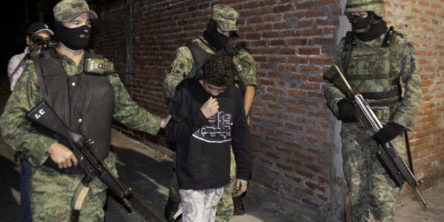 FILE - In this Dec. 3, 2010 file photo, Mexican soldiers present Edgar "El Ponchis" Jimenez Lugo to the media in the city of Cuernavaca, Mexico. The teenage U.S. citizen who acknowledged being a drug-cartel killer has finished his three year juvenile-offender term for homicide, kidnapping and drug and weapons possession. (AP Photo)