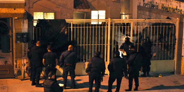 Oct. 22, 2010: Mexican federal police officers stand outside a home after the exterior gate was covered with a plastic tarp in the northern city of Ciudad Juarez, Mexico. At least 13 people were shot dead and 15 wounded in an attack on this house during a party in Ciudad Juarez, the second such massacre in less than a week in the violent border city.