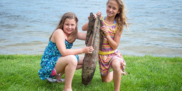Paige Burnett, 10, left, and Sage Menzies, 9 pose with a World War I practice bomb they discovered the day before while swimming in Lobdell Lake behind the Menzies' home in Linden, Mich.