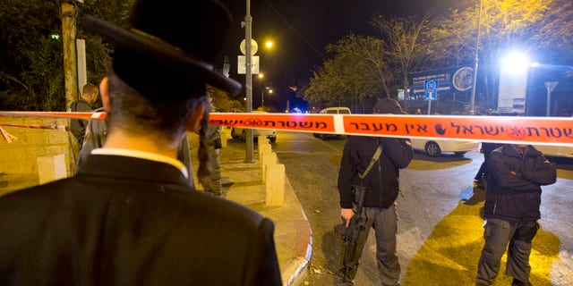Oct 29, 2014: An ultra-Orthodox Jewish man looks as Israeli police officers stand guard at the scene of a shooting in Jerusalem