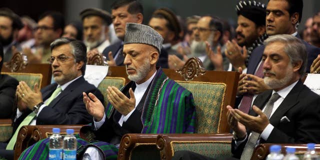 Afghan President Hamid Karzai, center, and Afghan presidential candidate Abdullah Abdullah pray during a ceremony marking the third anniversary of the assassination of former Afghan President Burhanuddin Rabbani in Kabul, Afghanistan, Saturday, Sept. 20, 2014. In 2011, an insurgent with a bomb wrapped in his turban assassinated Rabbani, who was leading a government effort to broker peace with the Taliban. (AP Photo/Rahmat Gul)