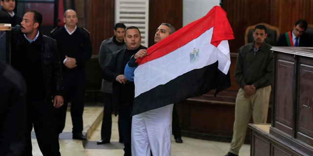 Feb. 12, 2015: Canadian Al-Jazeera English journalist Mohamed Fahmy holds up an Egyptian flag at a courthouse near Tora prison in Cairo. (AP Photo/Hassan Ammar)