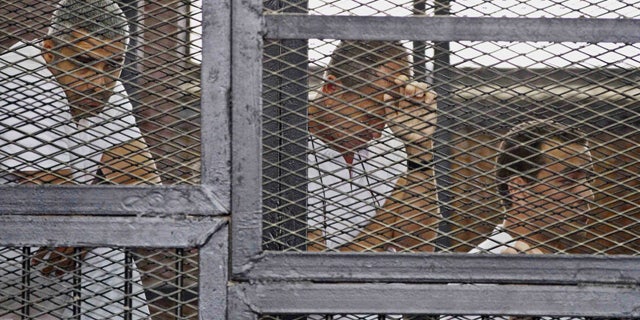 May 15, 2014: In this file photo, from left, Mohammed Fahmy, Canadian-Egyptian acting bureau chief of Al-Jazeera, Australian correspondent Peter Greste, and Egyptian producer Baher Mohamed appear in a defendant's cage along with several other defendants during their trial on terror charges at a courtroom in Cairo. (AP)