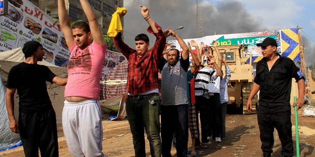 FILE - In this Wednesday, Aug. 14, 2013 file photo, Egyptian security forces detain protesters as they clear a sit-in by supporters of ousted Islamist President Mohammed Morsi in the eastern Nasr City district of Cairo. The scene on Aug. 14, 2013, was the start of the biggest massacre in modern Egyptian history, as security forces crushed the sit-in by Islamist supporters of Mohammed Morsi, the elected president who had been removed by the military a month earlier. At least 624 people were killed during 12 hours of mayhem in Cairo’s Rabaah el-Adawiyah Square, though rights groups have said the toll may be several hundred higher. (AP Photo/Ahmed Gomaa, File)