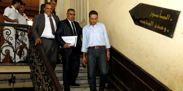 In this Thursday, Aug. 23, 2012 photo, Newspaper editor Islam Afifi, right, walks out of a Cairo police station hours after a court had ordered Afifi to remain in prison pending trial in September over accusations of slandering the president and harming public interest for inflammatory articles published in el-Dustour newspaper in Cairo, Egypt. Hours after the court decision was announced, President Mohammed Morsi passed his first law since assuming lawmaking powers banning the imprisonment of journalists who face trial on media-related charges. (AP Photo/Ahmed Abd el Fatah