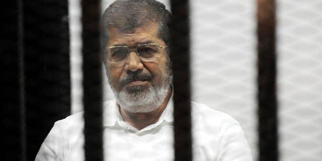 FILE - In this file photo taken Monday, Nov. 3, 2014, Egypt's ousted Islamist President Mohammed Morsi sits in the defendant cage in the Police Academy courthouse during a court hearing on charges of inciting the murder of his opponents, in Cairo, Egypt. Egypt's state news agency said prosecutors have asked for the death sentence for Morsi and other Muslim Brotherhood leaders on trial on espionage charges. (AP Photo/Mohammed al-Law, File)