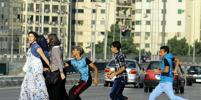FILE -- In this Monday, Aug. 20, 2012 file photo, an Egyptian youth, trailed by his friends, gropes a woman crossing the street with her friends in Cairo, Egypt. Abdel-Fattah el-Sissi, Egypt's newly sworn-in president, has apologized in person to a woman who was sexually assaulted by a mob during weekend celebrations marking his inauguration. Several women were assaulted during the Sunday, June 8, 2014 inaugural festivities. (AP Photo/Ahmed Abd El Latif, El Shorouk Newspaper, File)   EGYPT OUT