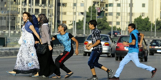 Aug. 20, 2012 - FILE photo of Egyptian youth groping a woman crossing the street in Cairo, Egypt. Abdel-Fattah el-Sissi, Egypt's newly sworn-in president, has apologized in person to a woman who was sexually assaulted by a mob during weekend celebrations marking his inauguration. Several women were assaulted during the June 8th inaugural festivities.