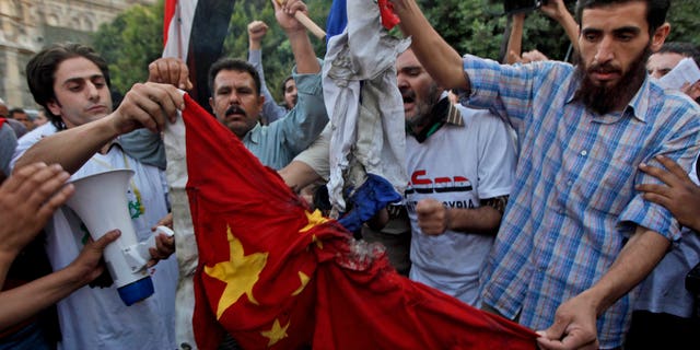 Syrian protesters burn the national flags of China and Russia during an anti-Syrian regime protest in front of the Arab league headquarters in Cairo, Egypt Sunday, Oct. 16, 2011.