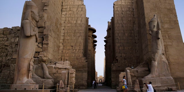 FILE - In this Sunday, Nov. 30, 2014, file photo a tourist has her picture taken at the ruins of the Karnak Temple in Luxor, Egypt. Egyptian officials say a suicide bomber has blown himself up at the ancient temple of Karnak in Luxor, a southern city frequented by millions of foreign and Egyptian tourists every year. (AP Photo/Hassan Ammar, File)