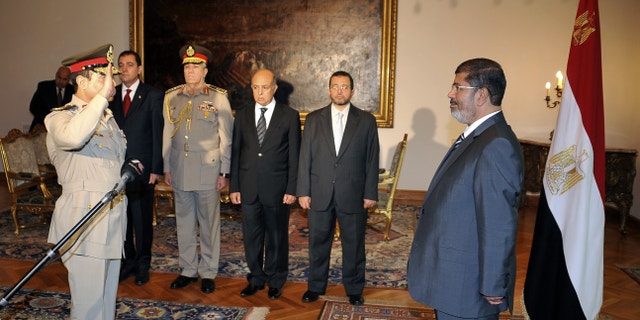 RETRANSMISSION FOR ALTERNATIVE CROP - Egyptian President Mohammed Morsi, right, swears in newly-appointed Minister of Defense, Lt. Gen. Abdel-Fattah el-Sissi, left, in Cairo, Egypt, Sunday, Aug. 12, 2012. Egypt's Islamist president ordered his former defense minister and chief of staff to retire on Sunday and canceled the military-declared constitutional amendments that gave top generals wide powers. (AP Photo/Egyptian Presidency)