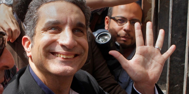 Popular Egyptian television satirist Bassem Youssef, who has come to be known as Egypt's Jon Stewart, waves to is supporters as he enters Egypt's state prosecutors office to face accusations of insulting Islam and the country's Islamist leader in Cairo, Egypt, Sunday, March 31, 2013. Government opponents said the warrant against such a high profile figure, known for lampooning President Mohammed Morsi and the new Islamist political class, was an escalation in a campaign to intimidate critics. (AP Photo/Amr Nabil)