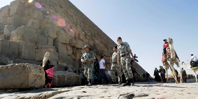 Nov. 11, 2011: Egyptian soldiers walk at the base the pyramid of Khufu, largest of the Giza Pyramids in Cairo, Egypt.