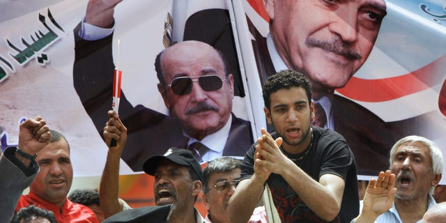 April 8, 2012: Supporters of former Egyptian Vice President Omar Suleiman chant in front of his posters out side the Higher Presidential Elections Commission, in Cairo, Egypt.