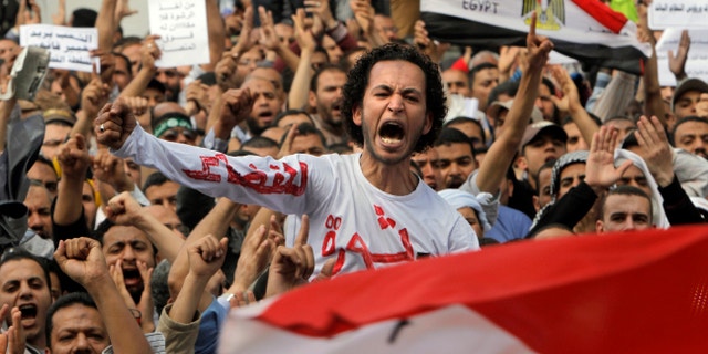 April 19, 2013 - Egyptian Muslim Brotherhood members shout slogans during a protest in front of the Supreme Judicial Council in Cairo, Egypt. Arabic on the T-shirt reads, "clean judiciary."