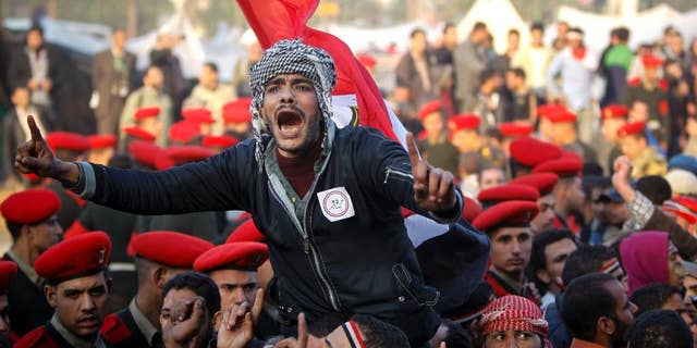 FILE - In this Feb. 13, 2011 file photo, remaining Egyptian protesters shout slogans as they are surrounded by army soldiers trying to lead them away from Tahrir Square in Cairo, Egypt. Within days, a cheering world community was riveted to screens as Egypt's long-submissive people thronged to Cairo's Tahrir Square, braving bullets and refusing to leave until veteran ruler Hosni Mubarak stepped down. (AP Photo/Tara Todras-Whitehill, File)